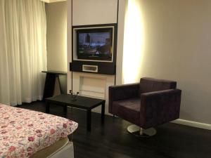 um quarto de hotel com uma cadeira e uma televisão em Apto Privativo em Hotel de Luxo no Ibirapuera em São Paulo
