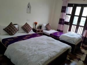 three beds in a room with windows at Hotel small town guest house in Bandipur +7 photos