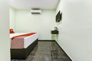 een slaapkamer met een bed en een tv aan de muur bij OYO 90445 Th Hotel in Bahau