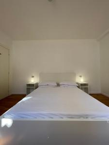 1 cama blanca grande en una habitación blanca con 2 mesas en Casa Apolloni 40 en Fano