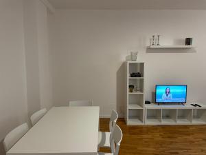 a white living room with a white table and a tv at Casa Apolloni 40 in Fano