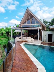 a house with a swimming pool and a wooden deck at Stay at My Place Bali in Canggu