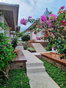 un jardin avec des fleurs roses, des escaliers et des bancs dans l'établissement Stay at My Place Bali, à Canggu