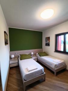 2 camas en una habitación con una pared verde en B&B Rio Rai, en Gemona del Friuli