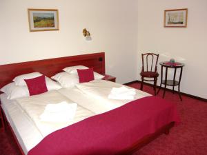 a bedroom with a large bed with a red blanket at Adler Hotel in Budaörs