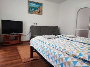 a bedroom with a bed and a flat screen tv at BM Apartman in Zalakaros