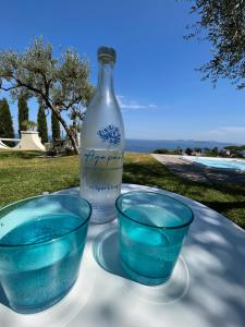 イスキアにあるAgapanto Luxury Accommodationの- 青いボウル2本、テーブルの上のボトル1本
