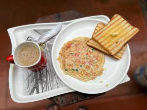 a plate of eggs and toast and a cup of coffee at Fatima Guest House in Baga