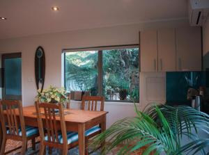 eine Küche mit einem Holztisch und Stühlen sowie einem Fenster in der Unterkunft Ponga eco-lodge in Hahei
