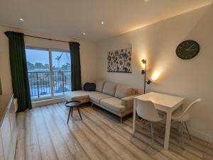 a living room with a couch and a table and a clock at Hounslow Apartments by Charles Hope in Hounslow