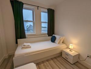 a small bedroom with a bed and a window at Hounslow Apartments by Charles Hope in Hounslow