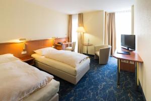 バイロイトにあるホテル ラインゴールドのベッド2台、デスク、テレビが備わるホテルルームです。