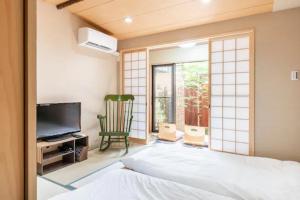 a bedroom with a bed and a tv and a window at Minami Toji---JP Style Guesthouse in Kyoto in Kyoto