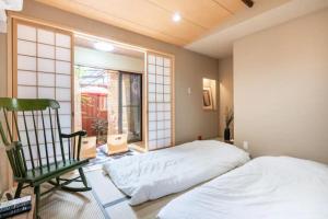 a bedroom with a bed and a chair and a window at Minami Toji---JP Style Guesthouse in Kyoto in Kyoto