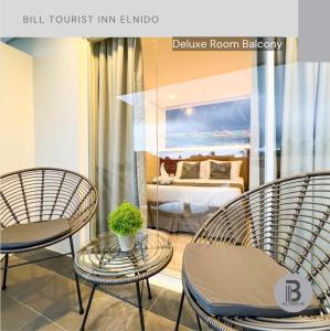 three chairs and a table in a room with a bed at Bill Tourist Inn in El Nido