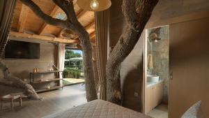 een slaapkamer met een boom die uit het plafond groeit bij Stolidi Mou Treehouse in Atsipopoulo