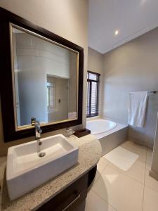 a bathroom with a sink and a bath tub at Sofala Lodge in Mokopane