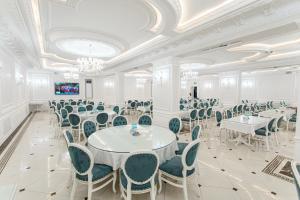 une grande pièce avec des tables et des chaises et une télévision dans l'établissement Konstantin Plaza, à Samarcande