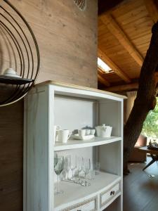 a white shelf with glasses and wine glasses at Stolidi Mou Treehouse in Atsipopoulo