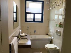 a bathroom with a tub and a toilet and a sink at House Vos in Hermanus +29 photos