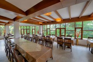 a dining room with tables and chairs and large windows at Silver Sand Sentinel in Port Blair