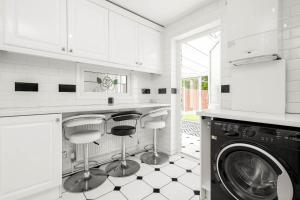 a white kitchen with a washing machine and stools at Modern 4 bedroom home ideal for Contractors, Groups and families ,FREE parking for multiple vehicle's in Birmingham