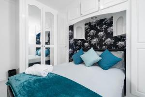 um quarto com uma cama branca e almofadas azuis em Modern 4 bedroom home ideal for Contractors, Groups and families ,FREE parking for multiple vehicle's em Birmingham