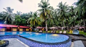 a swimming pool in front of a resort with palm trees at Silver Sand Beach Resort Havelock in Havelock Island