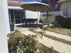 eine Terrasse mit einem Tisch und einem Sonnenschirm in der Unterkunft Jolie maison sur Ors (Oléron) jusqu'à 6 voyageurs in Grand-Village-Plage