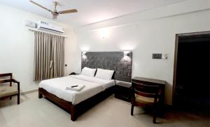 a bedroom with a bed and a chair in it at PPH Living Athithi Inn Corporate Stay in Coimbatore