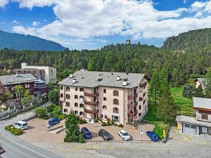 an apartment building with cars parked in a parking lot at La Planüra 15 in Maloja