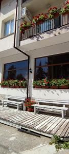 two benches in front of a building with flowers at Guest House Edelweiss in Govedartsi