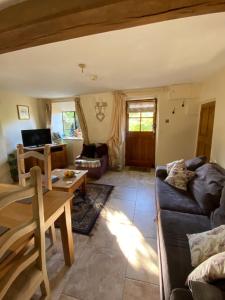 a living room with a couch and a table at Dove Cottage in Bisley