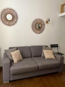 a gray couch in a living room with two mirrors at STUDIO MARCHE PROVENCAL in Antibes