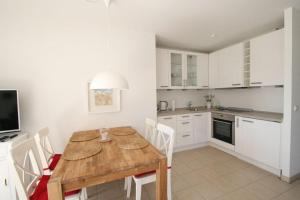 a kitchen with a wooden table and white cabinets at Villa Gesine App 01 - Strandkorb in Nienhagen