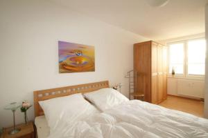 - une chambre avec un lit blanc et une peinture murale dans l'établissement Haus Odin App 24, à Graal-Müritz