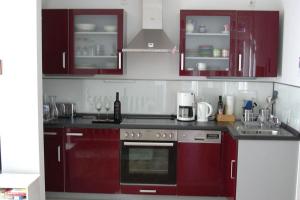 una cucina con armadi rossi e un piano cottura. di Haus Bucheneck App 07 a Graal-Müritz