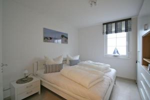 a bedroom with a bed with white sheets and a window at Villa Brigitte App 01 - Arielle in Nienhagen