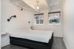 een slaapkamer met een bed in een kamer met 2 ramen bij Apartment Eewal 68 in Leeuwarden