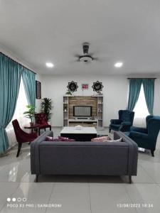 a living room with a grey couch and chairs at Sehmi's Homestay, Pagoh, Muar in Pagoh