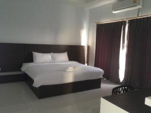 a bedroom with a large bed and a window at Praiyanan Place Hotel in Maha Sarakham