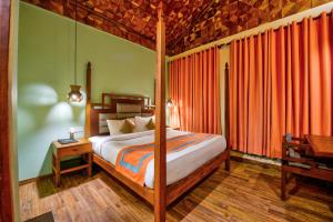 a bedroom with a bed with orange curtains and a table at Silver Sand Village Resort in Havelock Island