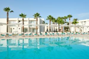 a pool with chairs and palm trees in front of a building at Iberostar Cala Domingos All Inclusive in Calas de Mallorca