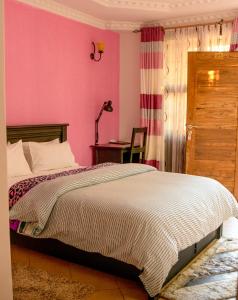 a bedroom with a bed and a pink wall at Samanene Hotel in Mwanza