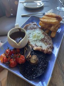 a blue plate of food with meat and french fries at Balcomie Links Hotel in Anstruther