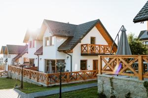 ein Haus mit einem Balkon und einem Sonnenschirm in der Unterkunft Czorsztyn View Apartamenty in Czorsztyn