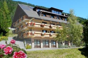 een groot gebouw met bloemen ervoor bij Appartements Herwig Schwarzenbacher in Weissensee