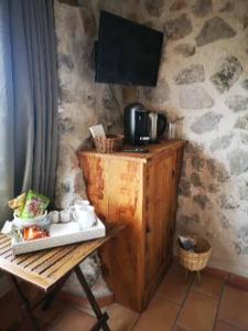 Una habitación con una mesa de madera y un televisor en la pared. en Le Cabanon de Gourdon bergerie rénové en pierre vue mer, en Gourdon