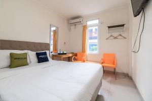 - une chambre avec un grand lit blanc et des chaises orange dans l'établissement Urbanview Hotel Minongga Pondok Labu by RedDoorz, à Jakarta
