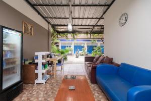 un salon avec un canapé bleu et une télévision dans l'établissement Urbanview Hotel Minongga Pondok Labu by RedDoorz, à Jakarta